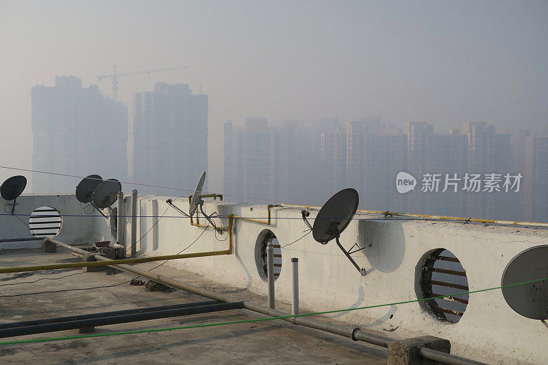 印度北方邦新德里的印度公寓楼屋顶的图片，通过墙上的洞显示早晨雾蒙蒙的天空污染，被污染的雾蒙蒙的天空，德里污染的照片汽车尾气/工厂排放